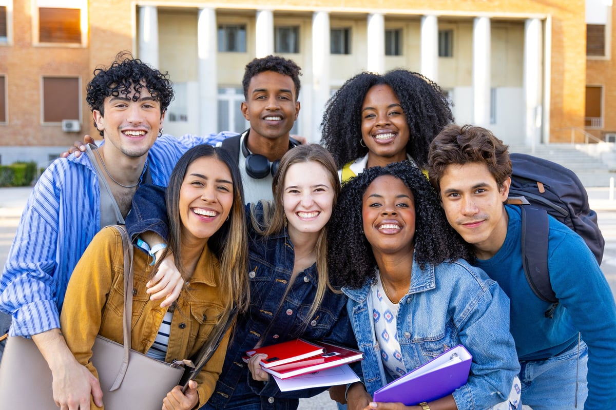 Happy diverse students posing together on university campus, embracing friendship and education