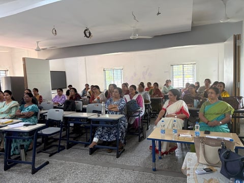 Large group of women gathered in a bright classroom for a community meeting or training session